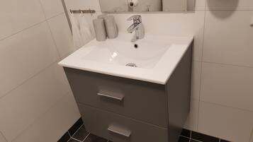 A bathroom with a white sink, a mirror, and a toilet paper holder.