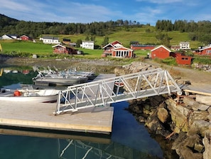 A dock with boats, a wooden pier, and houses in a rural setting. - Aa Gård (Lavangen)