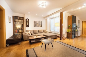 Un salón espacioso con un sofá modular, un pequeño otoman, una estantería y una mesa de centro.