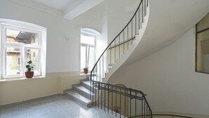 Un intérieur spacieux agrémenté d’un escalier en colimaçon, de grandes fenêtres et de plantes en pot.