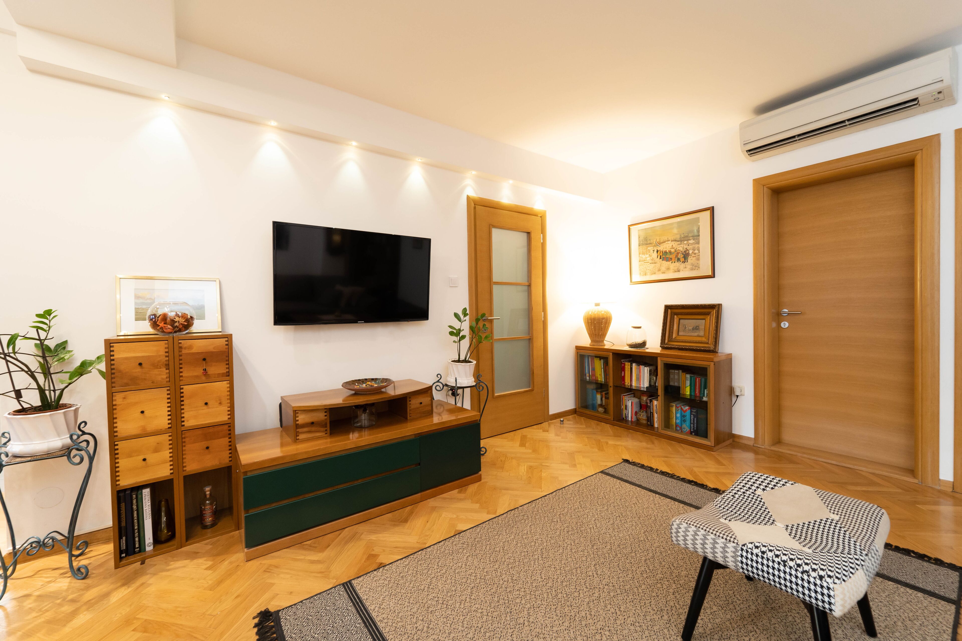 Ein Wohnzimmer mit Holzschrank, Fernseher, Bücherregal und einer Tür.