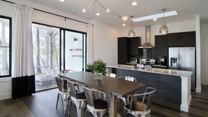 Une cuisine moderne dotée d’un îlot central, d’appareils électroménagers en acier inoxydable et d’un coin repas avec une table et des chaises.