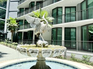 Ein Brunnen mit einer Schwanstatue vor einem modernen Gebäude mit Balkonen und großen Fenstern.