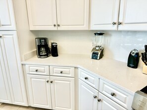 A kitchen with white cabinets, a coffee maker, a blender, and a toaster.