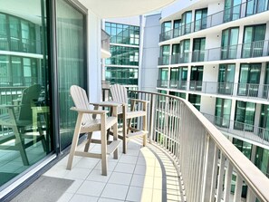 A modern building with multiple balconies, each with glass railings and outdoor seating.
