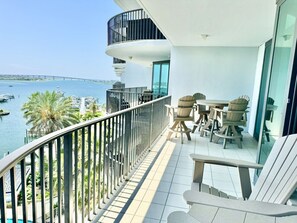 A balcony with a view of the sea, outdoor furniture, and a railing.