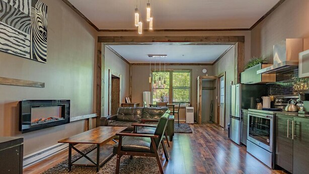 A modern kitchen with built-in appliances, a dining area with a leather sofa, and a fireplace.