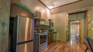 A compact kitchen with a stainless steel refrigerator, double oven, and microwave.