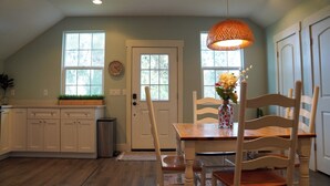 Una cocina con armarios blancos, una mesa de comedor de madera y una lámpara colgante.