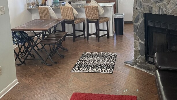 Una cocina moderna con chimenea de piedra, zona de comedor con sillas y una alfombra roja.