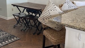 Un comedor con una mesa y sillas de madera, un candelabro, un cuadro enmarcado y una alfombra.