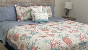 Una cama con colcha estampada, cabecero de madera y lámpara de noche.