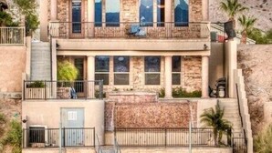 Un edificio de varios pisos con fachada de piedra, balcones y una zona de piscina.