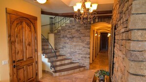 Una puerta de madera, una escalera con paredes de piedra y un candelabro.