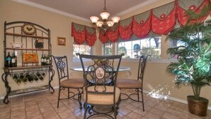 A dining area with a round table and four chairs, a wine rack with bottles, and a chandelier. - Granbury's  Luxurious  'Abbey Manor'. Walk to Historic Square (Granbury)