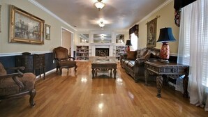A spacious living room with hardwood flooring, a fireplace, a coffee table, and a sofa. - Granbury's  Luxurious  'Abbey Manor'. Walk to Historic Square (Granbury)