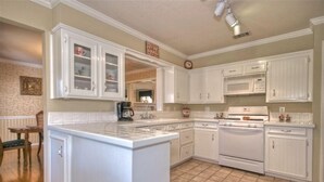 A kitchen with white cabinetry, a central island, a microwave, and an oven. - Granbury's  Luxurious  'Abbey Manor'. Walk to Historic Square (Granbury)
