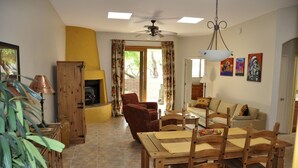 Un salon avec une cheminée, une table à manger avec des chaises, un canapé et un ventilateur de plafond.