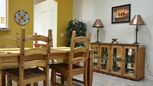 Un coin repas avec une table et des chaises en bois, un meuble avec des portes en verre et une plante en pot.