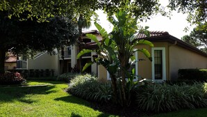 A two-story house with a well-maintained garden, including a large banana tree and various shrubs. - Ultimate Orlando Adventure: Orange Lake Resort - Disney, Universal, Sea World! (Kissimmee)