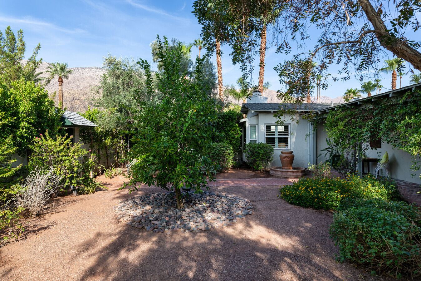 A well-maintained garden with a variety of plants and a small house with a window and a door.