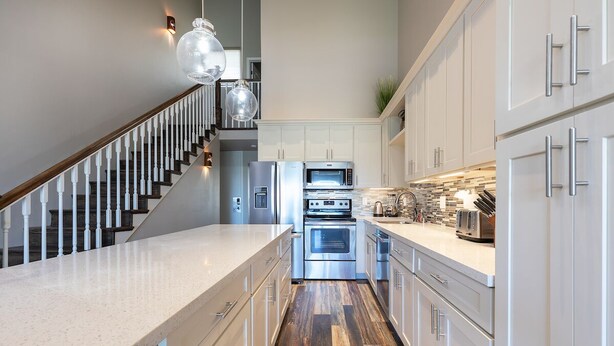 A modern kitchen with stainless steel appliances, white cabinetry, and a wooden floor. - Fantastic Ocean View Steps to Kamaole Beach 3 (Kihei)