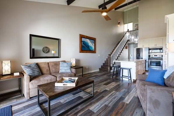 A spacious living area with a sofa, coffee table, and a kitchen in the background.