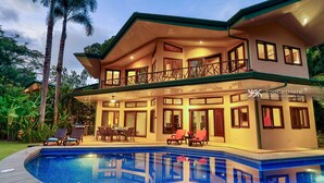 A two-story house with a swimming pool, outdoor seating, and a balcony.