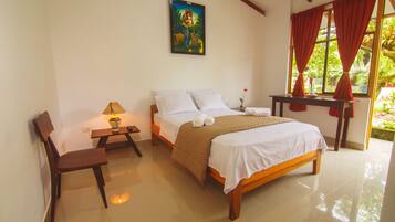 A bedroom with a bed, a chair, a table with a lamp, and a painting on the wall.