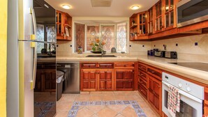 A kitchen with wooden cabinets, a stainless steel refrigerator, a dishwasher, a double oven, and a tiled backsplash. - Listen to the ocean at night! (puerta aventuras)