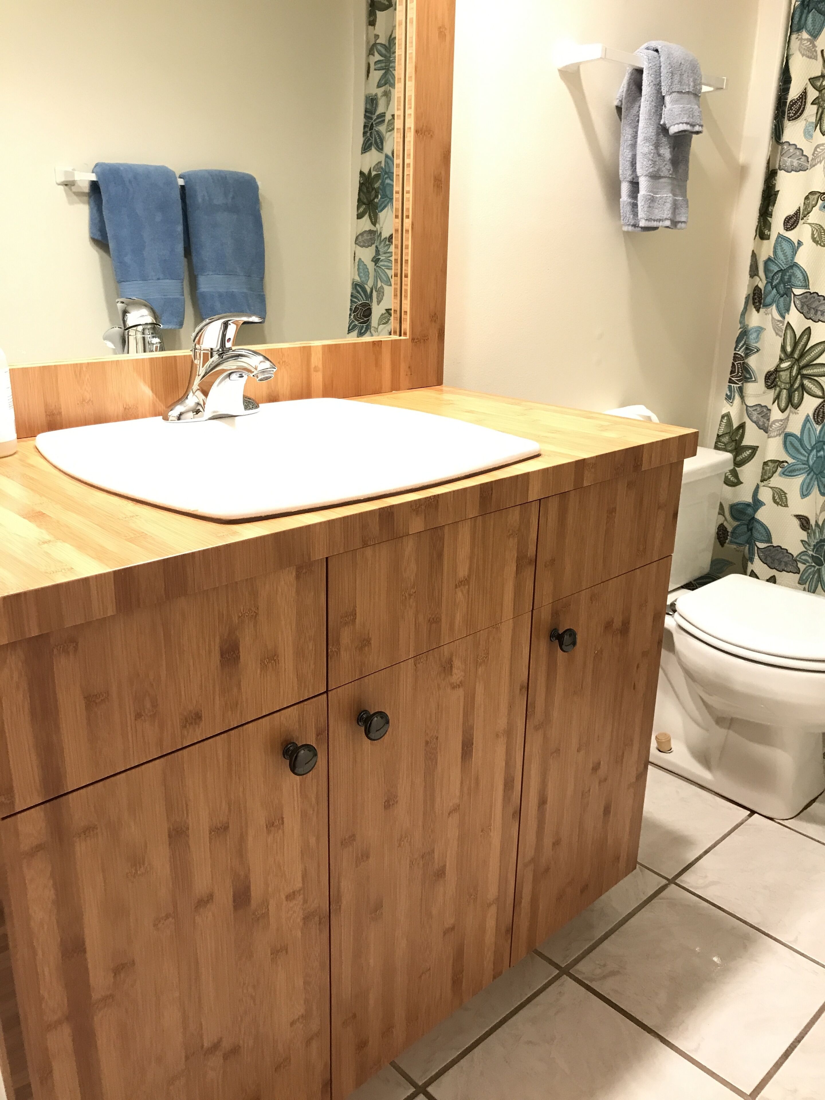 A bathroom with a wooden vanity, a white sink, a mirror, and a toilet.