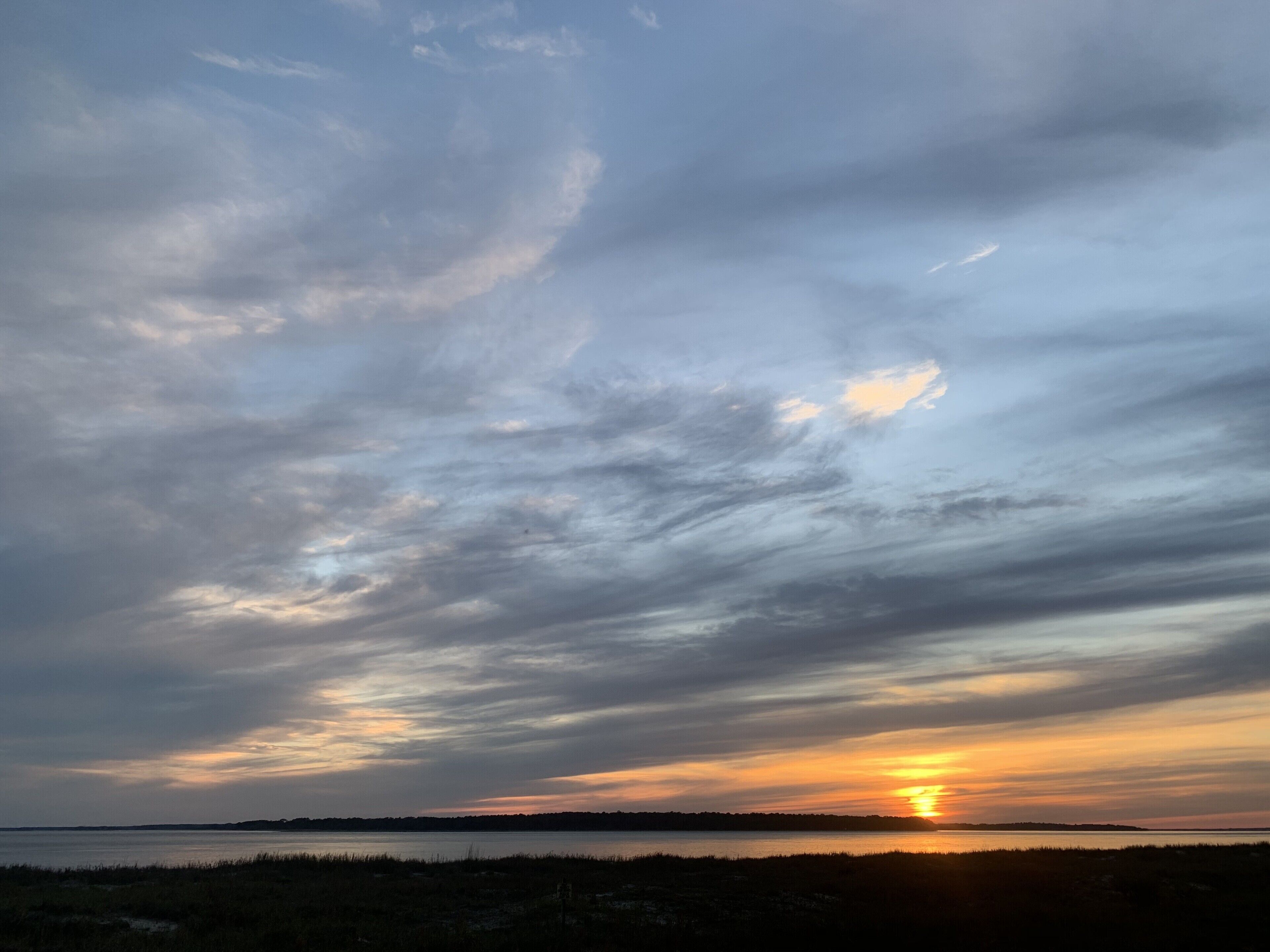 Un atardecer sobre una masa de agua con una costa lejana.
