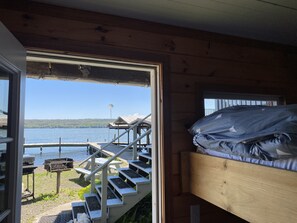 A cabin with a wooden interior, a bunk bed, a view of a lake, and a dock with a boat. - Great Cayuga Lake House Complex for families, reunions, or just relaxing! (Trumansburg)