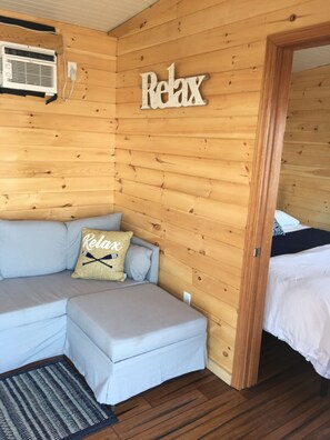 A cozy cabin room with a wooden interior, a sofa, and a bed. - Great Cayuga Lake House Complex for families, reunions, or just relaxing! (Trumansburg)