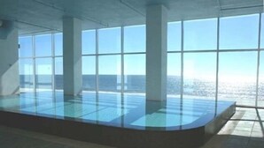 Una piscina interior moderna con amplios ventanales que ofrecen vistas al océano.