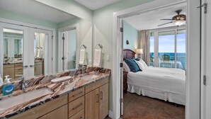 Habitación de hotel con baño de mármol, cama con vistas y balcón.