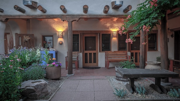 A rustic building with a covered patio, wooden benches, and a stone pathway.