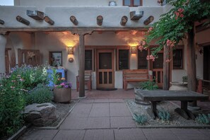 Un bâtiment rustique doté d’un patio couvert, de bancs en bois et d’un chemin en pierre.