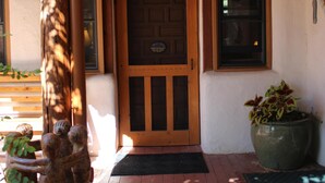 A wooden door with a window above it, a large planter with a statue, and a wooden ceiling.