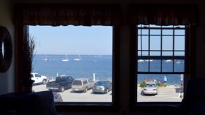 A room with a large window overlooking a parking area and the sea. - Maine Midcoast Vacation at Lincolnville Beach (Lincolnville)