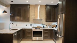 A modern kitchen with dark wood cabinets, a stainless steel oven, and a built-in microwave. - Amazing Penthouse-Private Hot Tub #5 of 5 - 405 (Canmore)
