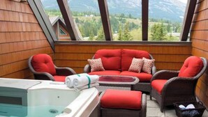 A cozy balcony with wicker furniture, a hot tub, and a view of mountains. - Amazing Penthouse-Private Hot Tub #5 of 5 - 405 (Canmore)