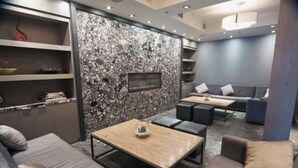 A modern living room with a stone wall, a wooden coffee table, grey sofas, and a flat-screen TV mounted on the wall. - Amazing Penthouse-Private Hot Tub #5 of 5 - 405 (Canmore)