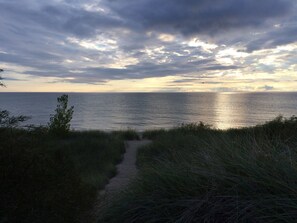 En kuststig som leder ner till havet, med en molnig himmel ovanför.