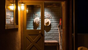 Una puerta de madera con un panel de vidrio, un banco y un perchero de pared con sombreros.