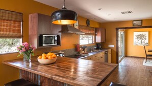 Una cocina con una isla grande, armarios de madera, microondas y una lámpara colgante.