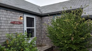 Una casa amb façana de fusta de color gris, una porta blanca i una caixa de correu vermella amb el número 640.