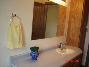 Een bad/douchecombinatie, handdoeken, zeep, toiletpapier