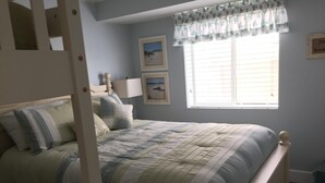 A bedroom with a bed, a window with blinds, and two framed pictures on the wall. - Ocean Front 1st Floor walkout to 25'x50' deck on the Boardwalk/Beach at 4th St (Ocean City)