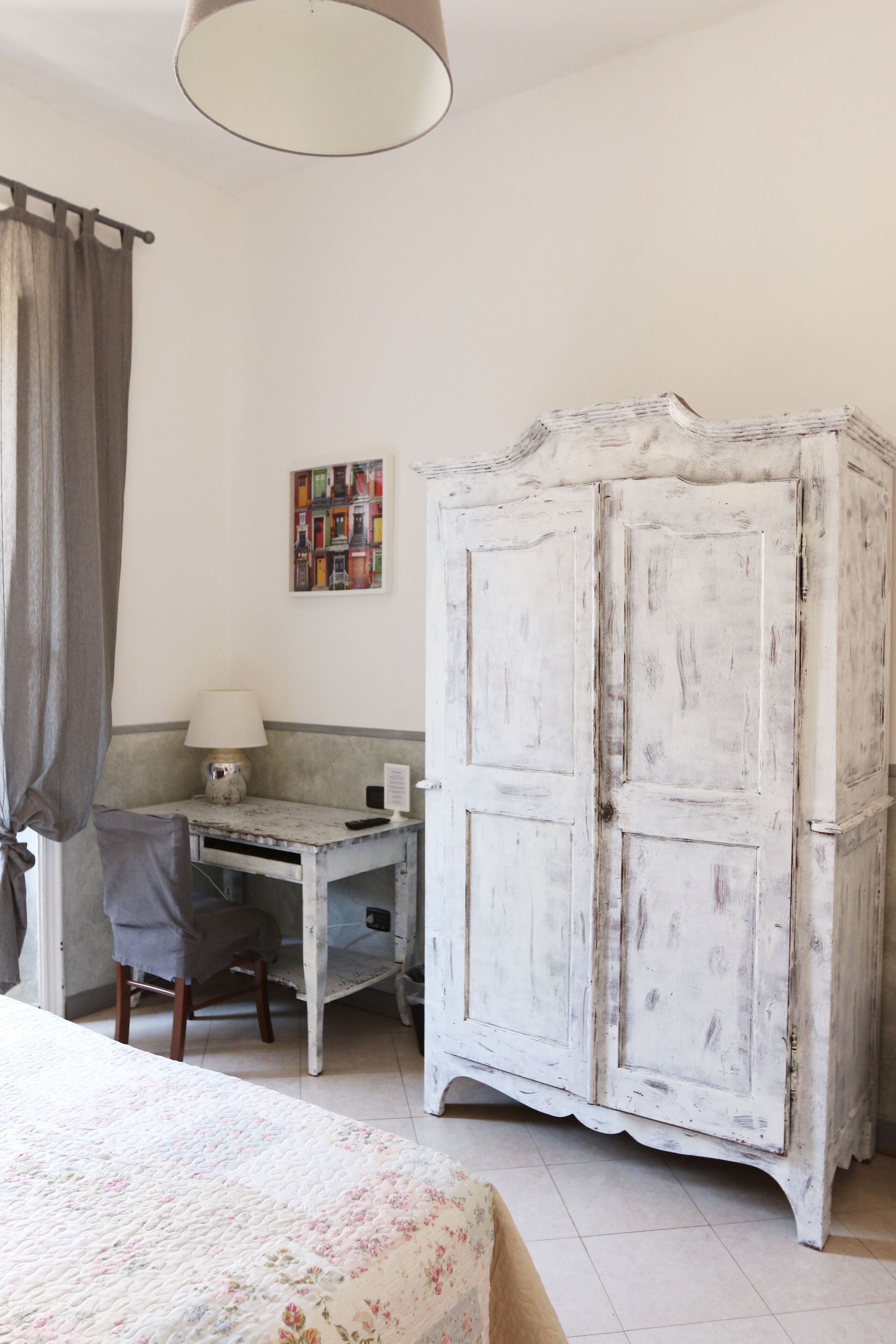 A room with a bed, a desk, a chair, and a white wardrobe.